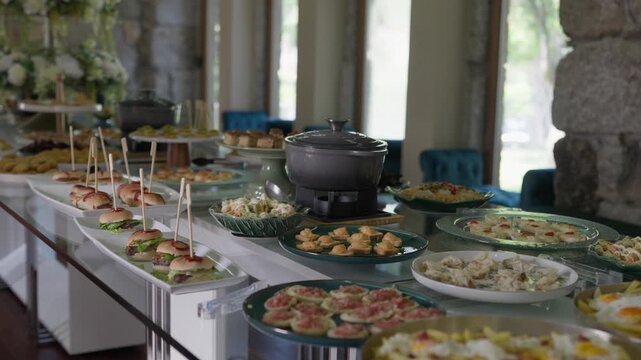 Long buffet table with mini sliders bruschetta and canapes served at a wedding reception