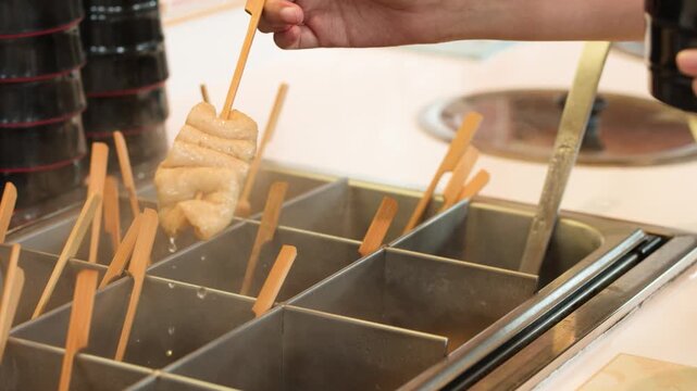 Hand Picking Korean Fish Cake Skewer From Hot Broth Container