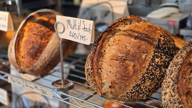 Loaf of bread with seeds.Whole grain churdough bread sits on the shelves in the bakery. The bread has a crisp, golden crust and a beautiful pattern, freshly baked from a variety of grains and seeds.