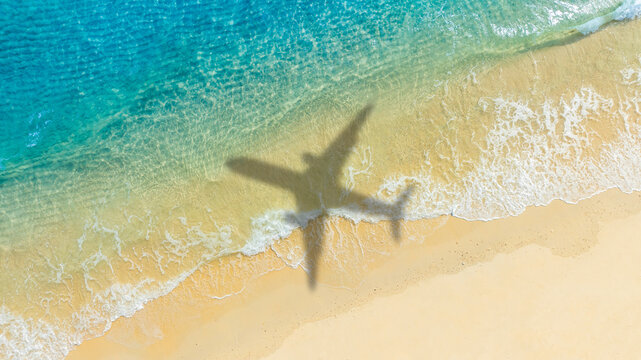 Aerial view of shadow passenger plane silhouette and sandy beach blue sea with waves at sea beach summer vacation sea travel concept	