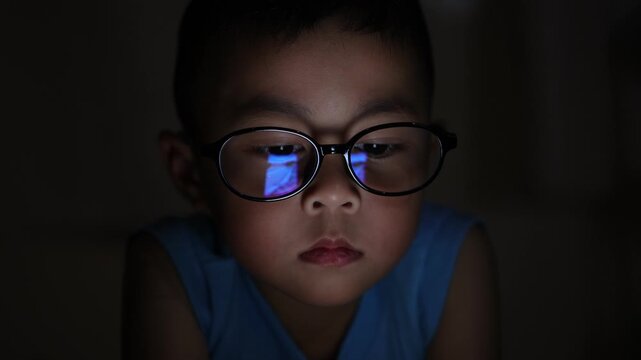 Kid using smartphone at night, The little boy is using a smartphone at home at night. Closeup of a little boy face in night, using phone, technology concept