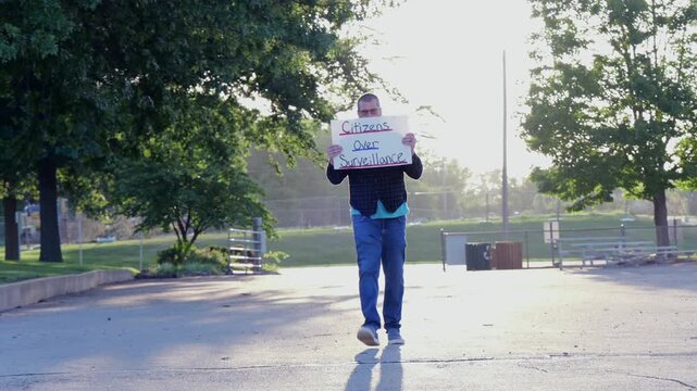 Demonstrator holding a Citizens Over Surveillance sign, protesting mass tracking, license plate readers, Fourth Amendment overreach illegal search