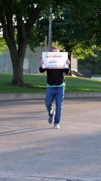 Demonstrator holding a Citizens Over Surveillance sign, protesting mass tracking, license plate readers, Fourth Amendment overreach illegal search