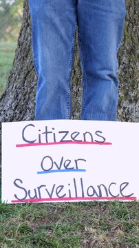 Demonstrator holding a Citizens Over Surveillance sign, protesting mass tracking, license plate readers, Fourth Amendment overreach illegal search