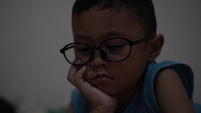The little boy is using a smartphone at home at night. Closeup of a little boy face in night, using phone, technology concept