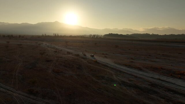 Cinematic Aerial Approach of an SUV and Motorcycle Driving on a Lahar Trail at Sunrise