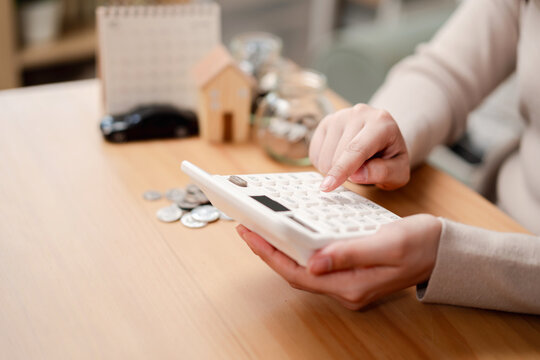 Woman hands holding white calculator for home and car loan planning. Personal finance and saving money for future goals concept.