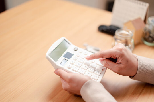 Woman hands holding white calculator for home and car loan planning. Personal finance and saving money for future goals concept.