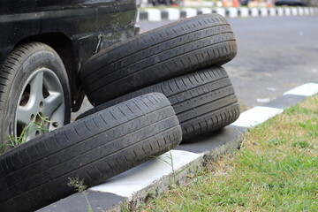 Obraz premium Stacked car tires beside parked vehicle wheel