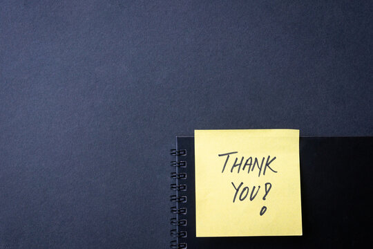 Thank You Note on Spiral Notebook, against black background. Copy space.