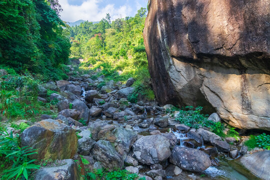 Apple shaped huge rock called "Apple Stone", with river flowing by side and blue sky in background , at Jhalong, Dooars, West Bengal - India