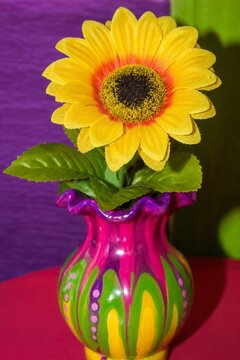 A cheap plastic flower in a garish vase, tacky aesthetic with bright colors.