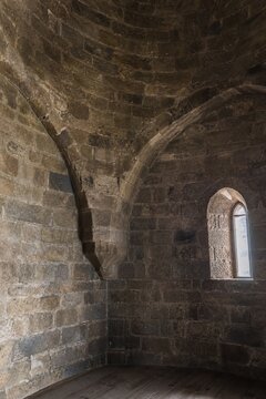 Interior of a round stone tower, corner where masonry walls curve inward to support the ceiling.