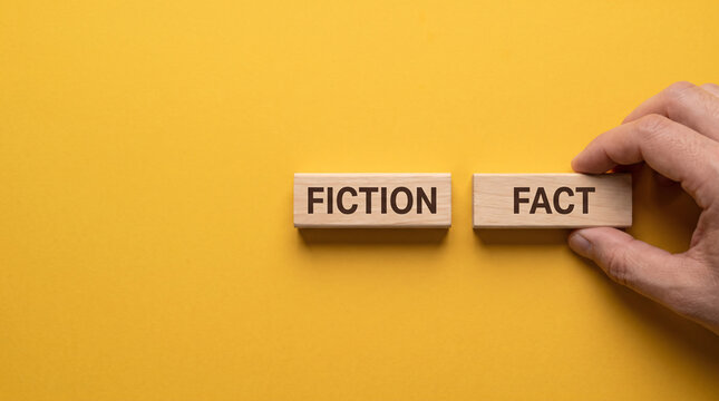 Hand placing wooden block labeled fact next to fiction label