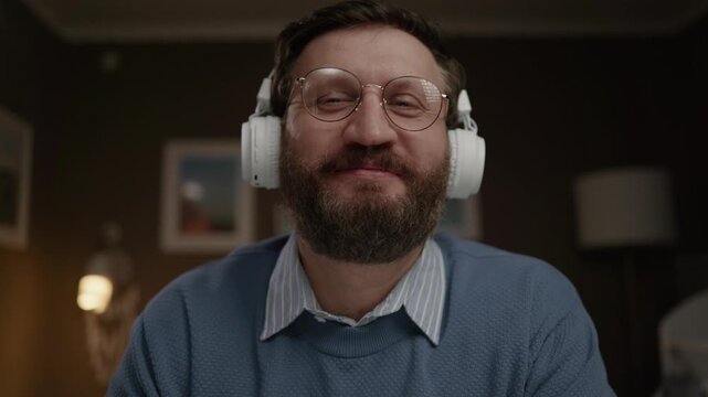 Man wearing headphones looking at camera and making respectful bow in greeting. Close-up