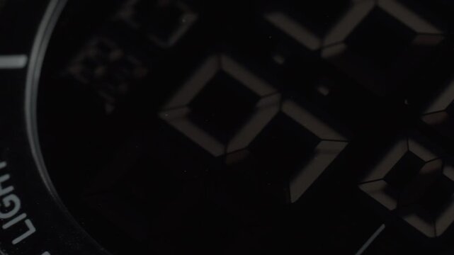 Macro close up of digital wristwatch display with 5 ATM marking and black watch bezel. Detailed timepiece footage showcasing electronic display, waterproof rating and design