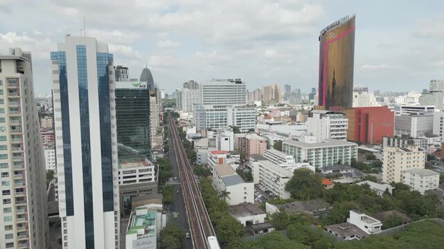 BTS Skytrain Rolls Into Ari Station Bangkok Thailand Drone Pan Up To Buildings And Sky 4K 60FPS