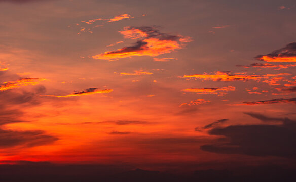 Orange and red sunset sky with glowing clouds, dramatic evening atmosphere and colorful cloudscape background. Warm natural weather scene. Nature and background design. Orange and crimson clouds.