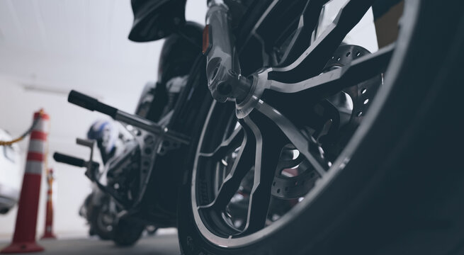 Closeup aluminum alloy wheel of motorcycle parked at car parking lot. Steel rims. Mag wheels of motorbike. Performance wheel and tire of motorcycle. Chrome disc brake and abs. motorbike accessory.