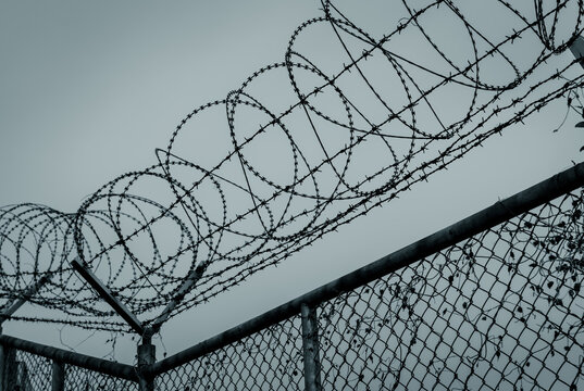 Prison security fence. Barbed wire security fence. Razor wire jail fence. Barrier border. Boundary security wall. Prison for arrest criminals or terrorists. Private area. Military zone concept.