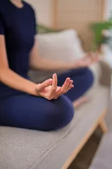 Fotobehang Lotusbloem Asian woman practicing meditation in lotus pose with mindful hand gesture during yoga session at home  © Audtakorn