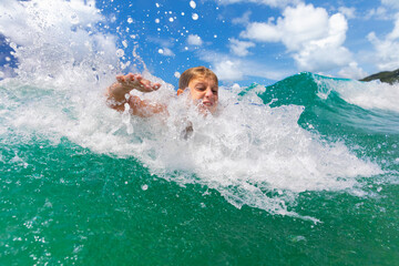 Young boy struggles in powerful ocean waves during summer vacation. Concept of water safety, rip currents, drowning risk and the importance of adult supervision while swimming in sea on beach holidays © Tropical studio