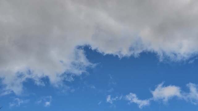 Blue sky with puffy white clouds drifts slowly. Cirrus clouds stretch across the heavens in wisps and swirls. Serene atmosphere suggests calm, peaceful weather