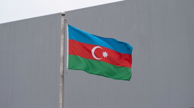 Azerbaijani flag waves proudly, blue, red, and green stripes with crescent and star, symbolizing national identity, heritage, and unity against plain backdrop.