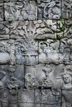 Textured close-up shot of historic andesite stone relief carvings on 9th-century temple wall