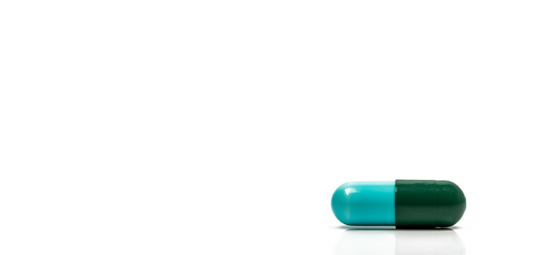 Blue and green antibiotic capsule pills isolated on white background in global healthcare concept showing antimicrobial resistance awareness and responsible drug use for infection treatment.