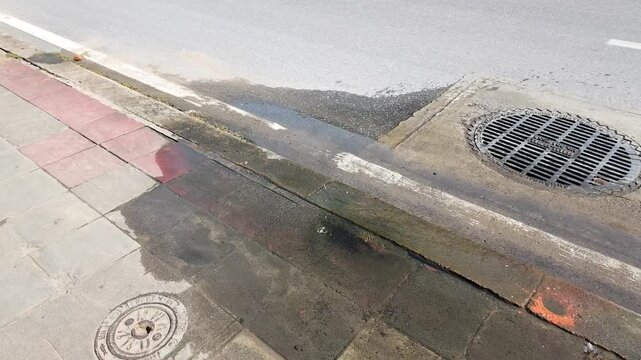 Wet City Sidewalk and Street Gutter with Metal Manhole Cover