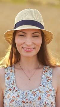 Woman wearing a hat posing, in outdoor sandy environment, with hat, necklace, from a frontal view perspective, with tan, blue accents, and relaxed and cheerful mood, nearby objects.