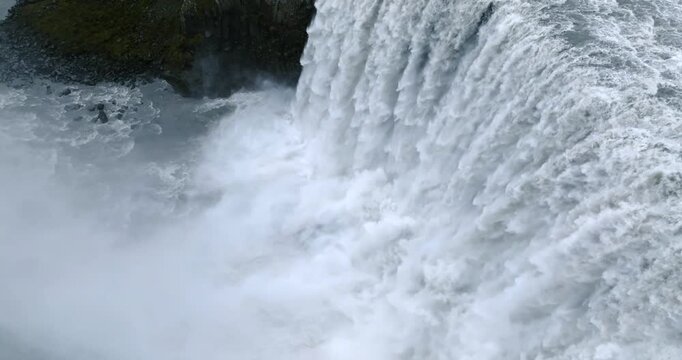 Dettifoss Waterfall crashes into Jokulsargljufur Canyon as the Jokulsa a Fjollum surges through towering basalt cliffs, filling the air with dense mist and whitewater, super slow motion aerial push in