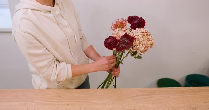 Professional floristry. Seasonal bouquet. Unrecognizable female floral designer arranging chrysanthemum flower composition in workshop.