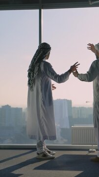 Two Muslim Arabic Entrepreneurs talking about Business Deals Corporate Plans Company Construction Investment in Modern Office Enterprise. Kandura Clothes.