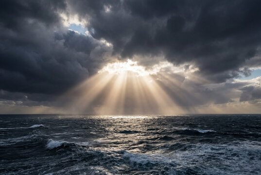 Dramatic sun rays breaking through dark stormy clouds over a choppy vast open ocean