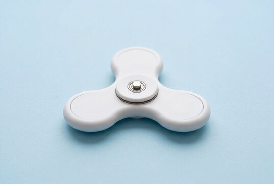 Plain white fidget spinner toy on a light blue surface