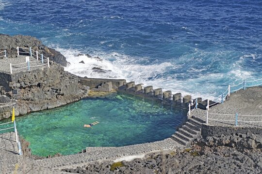 A swimming pool bordered by the sea with clear water on a rocky coast, Charco Azul, San Andres, La Palma, Canary Islands, Spain