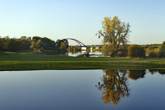 Calm lake with reflections of trees and a bridge behind it under a blue sky, flooded Elbe meadows, Elbe, Bridge of Unity Langendorf, Wendland, Lower Saxony, Germany