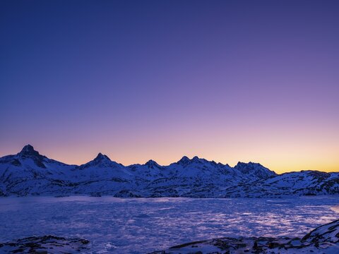 Snowy mountains above the frozen Kong Oscar Fjord at dawn, Tasiilaq, Ammassalik Island, Kommuneqarfik Sermersooq, East Greenland, Greenland