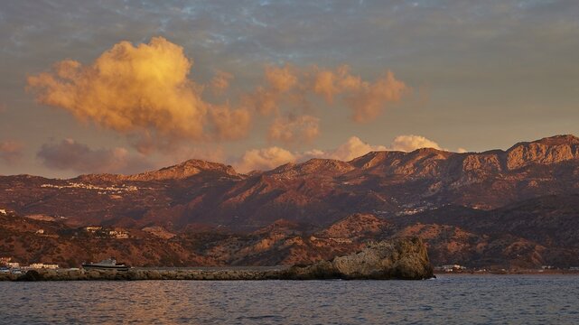 Sunrise on the coast with dramatic cloud formations and mountain landscape in the background, Pigadia, town and harbour, Pigadia Bay, main town, Karpathos, Dodecanese, Greek Islands, Greece