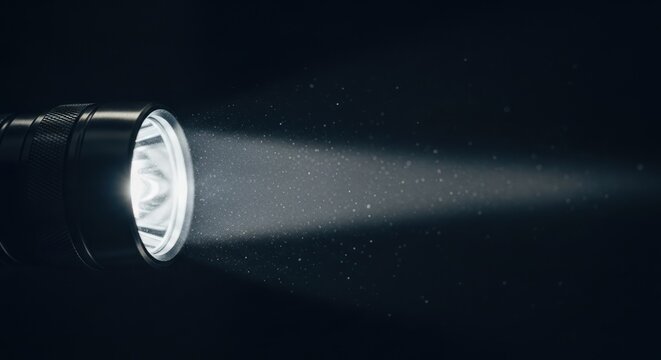 Close up of a flashlight with a beam of light against a dark background