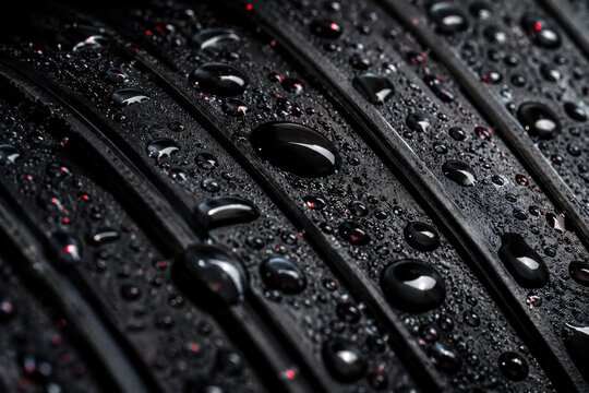 Clear water drops on a black striped surface with texture