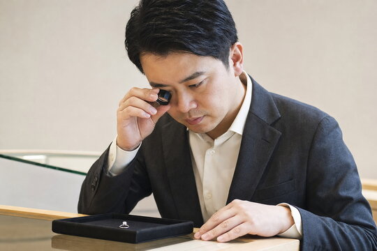 ルーペでダイヤモンドリングを鑑定する男性査定士
