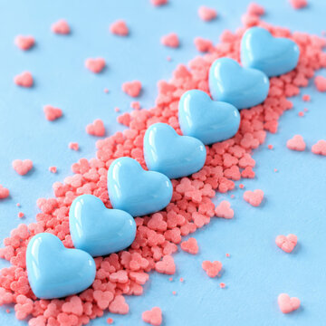 Blue heart shaped candies arranged in a row with pink sprinkles