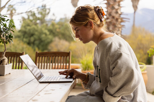 young woman using laptop computer on outdoor patio