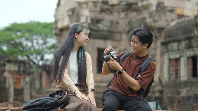 Young Asian Couple Sharing Travel Photos on Mirrorless Camera at Ancient Heritage Site