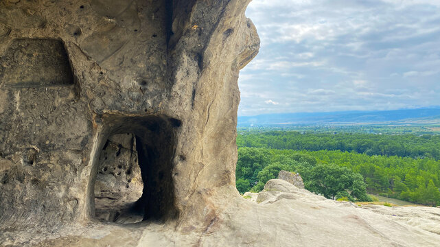 An ancient rock doorway opens from Uplistsikhe toward the green Mtkvari Valley, linking carved shelter architecture