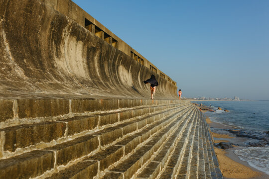 Three Sisters Running Along a Coastal Seawall at Golden Hour
