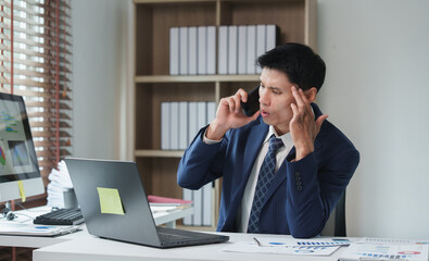 Obraz premium Businessman experiencing headache and stress during phone call